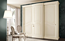 Wardrobe with 3 sliding doors and central curved hinged door, antique white glazed finish with decoration